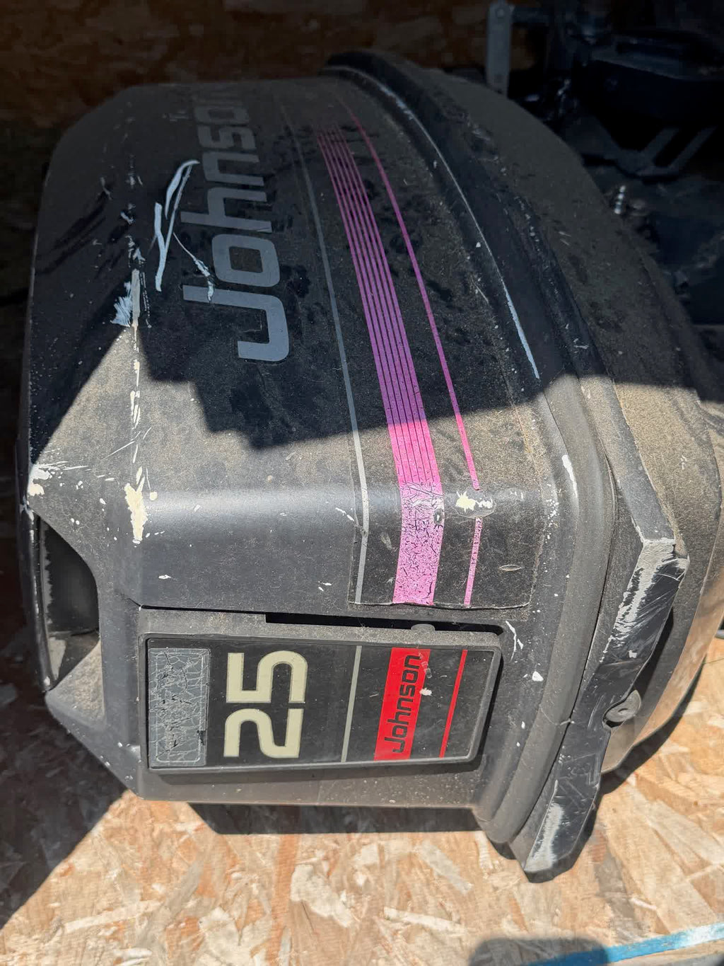 Johnson 25 HP outboard cowl with magenta stripe graphics, showing scuffs and storage dust