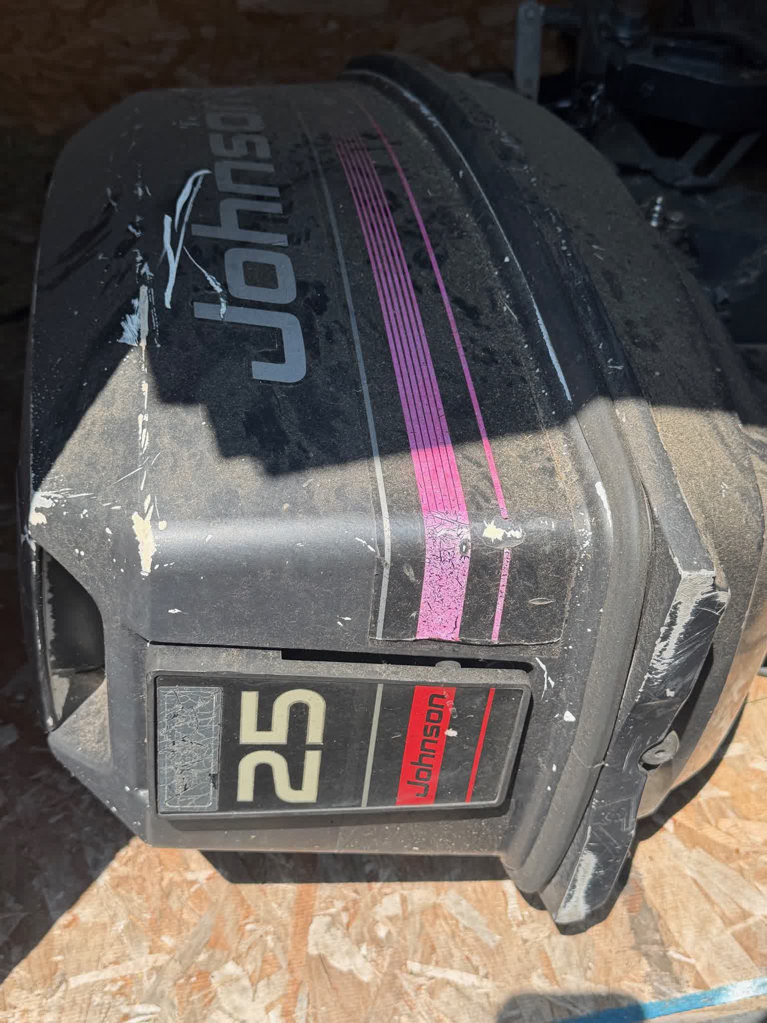 Johnson 25 HP outboard cowl with magenta stripe graphics, showing scuffs and storage dust